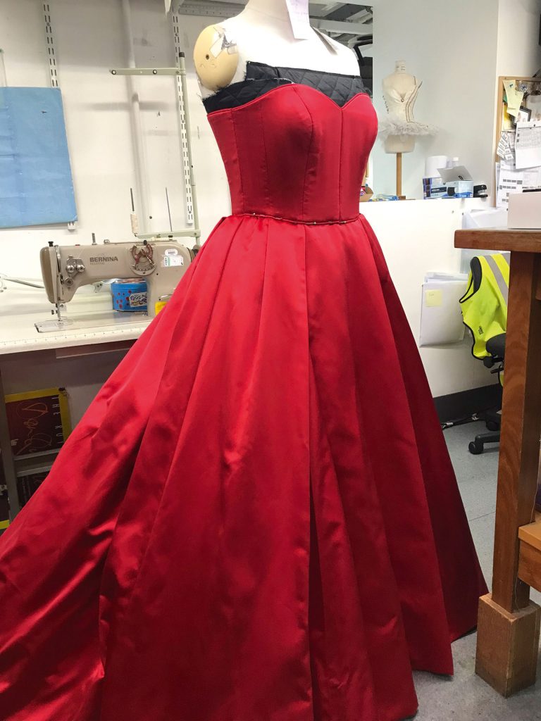Red sweetheart dress being altered by Amedine Bello for The Royal Opera House